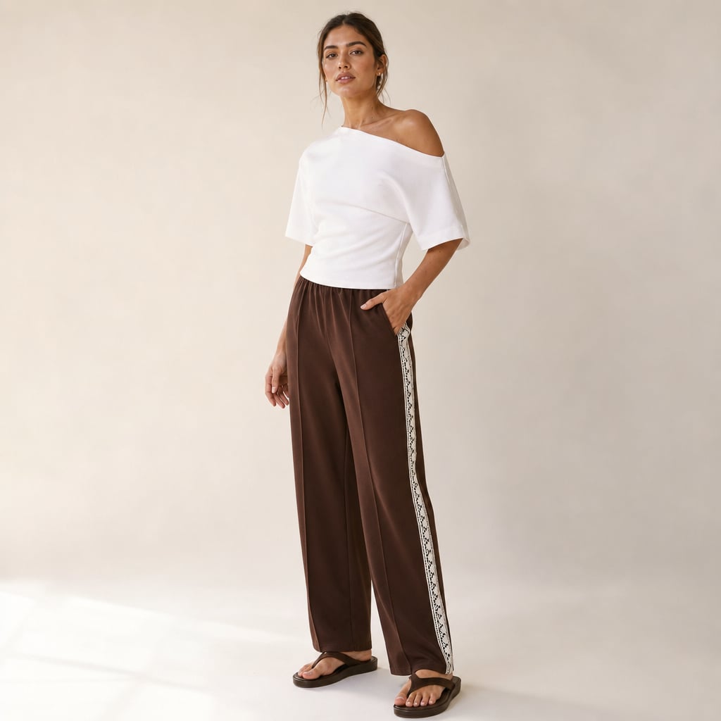 Modelo de frente con pantalón plisado chocolate, franja lateral visible de cadera a tobillo con orilla de encaje