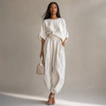 Modelo con conjunto de lino blanco blusa drapeada y pantalón pierna ancha tiro alto