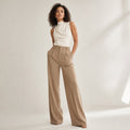 Modelo lleva pantalones anchos camel de tiro alto con caída recta hasta el tobillo