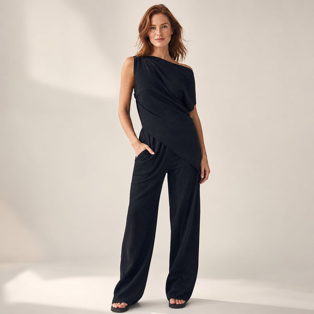 Modelo viste co-ord negro de hombro asimétrico y pantalón wide-leg hasta el piso