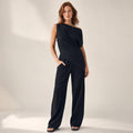 Modelo viste co-ord negro de hombro asimétrico y pantalón wide-leg hasta el piso