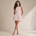 Modelo de frente mostrando la silueta A-line y el ribete de perlas en el cuello bote del vestido mini rosa
