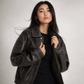 Modelo lleva bomber jacket oversized en tono carbón marrón con zip frontal y detalle de costura en contraste