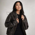 Modelo lleva bomber jacket oversized en tono carbón marrón con zip frontal y detalle de costura en contraste