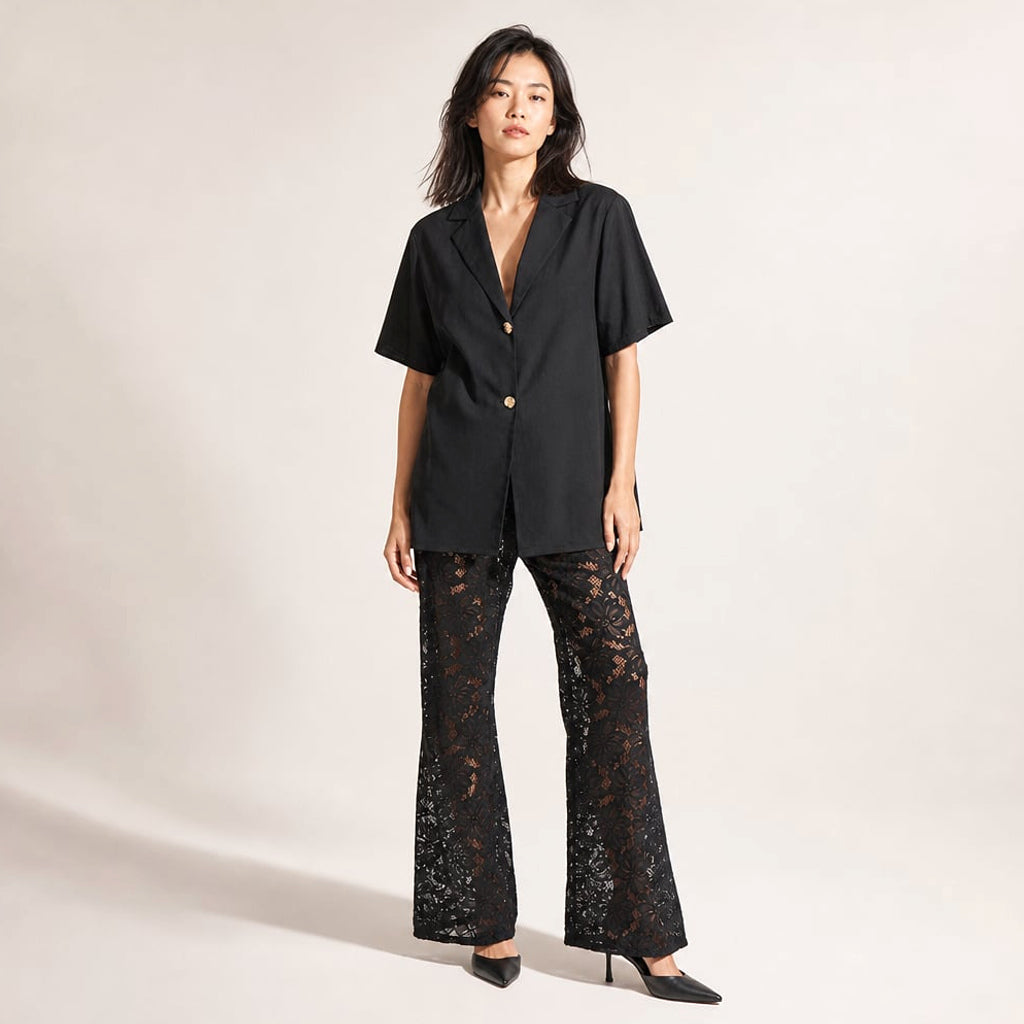 Modelo con conjunto negro de blusa algodón cuello en V y pantalón encaje pierna ancha, posando de frente