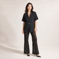 Modelo con conjunto negro de blusa algodón cuello en V y pantalón encaje pierna ancha, posando de frente