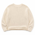 Modelo usando suéter de punto crema con cuello redondo y manga larga, look casual estructurado