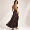 Modelo de pie con vestido maxi halter chocolate, hombros descubiertos y cut-out estructural en el corpiño, largo hasta el piso