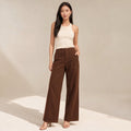 Modelo de pie con pantalones anchos de denim chocolate tiro alto que muestra la caída limpia de la pierna hasta el piso