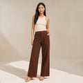 Modelo de pie con pantalones anchos de denim chocolate tiro alto que muestra la caída limpia de la pierna hasta el piso