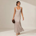 Modelo de frente con vestido maxi cuadros neutros, overlay que cae con movimiento, escote redondo y tirantes fijos