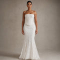 Modelo de pie con vestido maxi sirena blanco de encaje y corsé strapless, mostrando el vuelo de piso