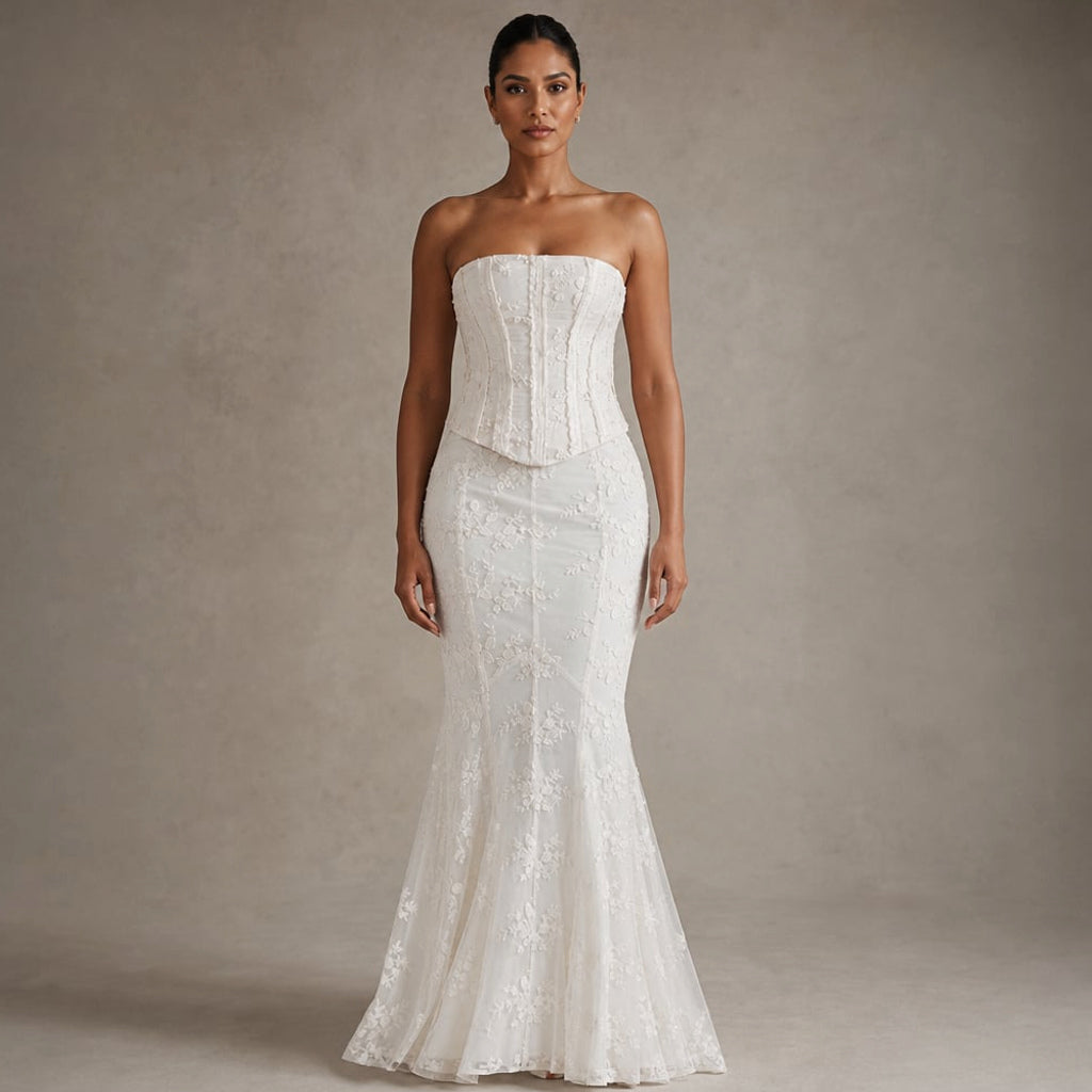 Modelo de pie con vestido maxi sirena blanco de encaje y corsé strapless, mostrando el vuelo de piso