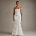 Modelo de pie con vestido maxi sirena blanco de encaje y corsé strapless, mostrando el vuelo de piso